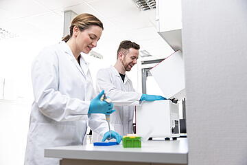 Two persons in a lab, pipetting